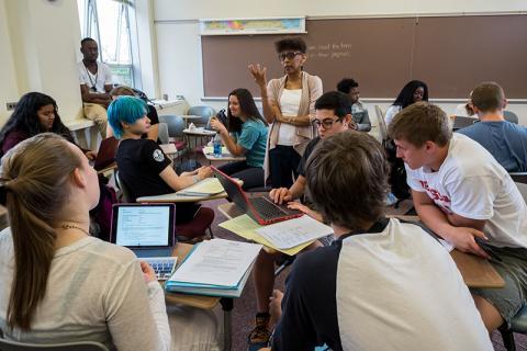 A professor speaks to students doing group work in a classroom