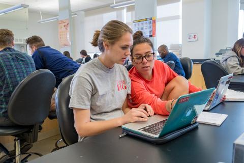 Two students working together at a laptop during class
